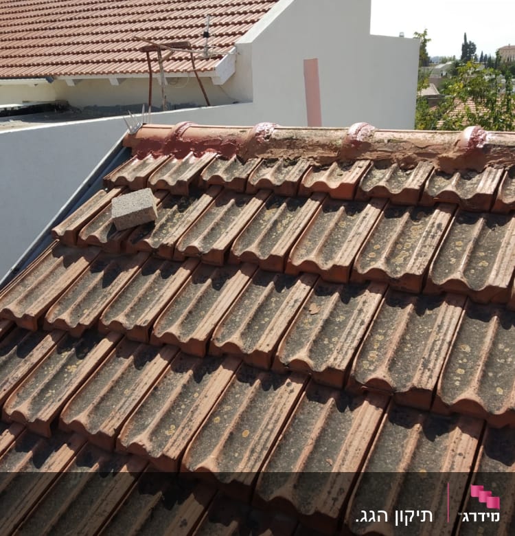 רעפים חומים על גג עם בלוק בטון מונח